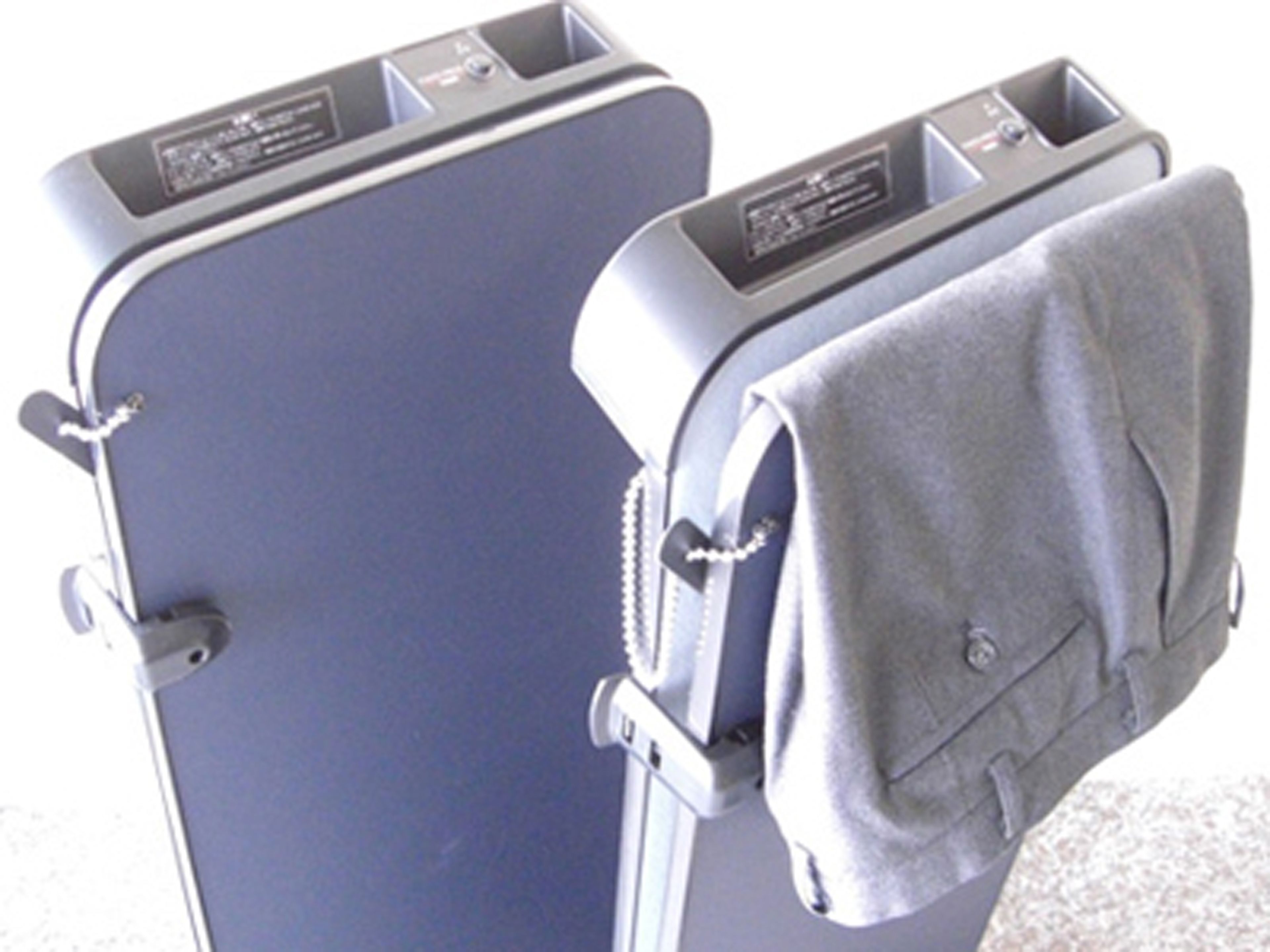 A blue suitcase with a grey garment hanging on the side.