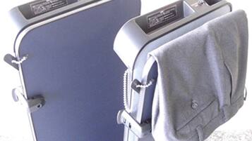 A blue suitcase with a grey garment hanging on the side.