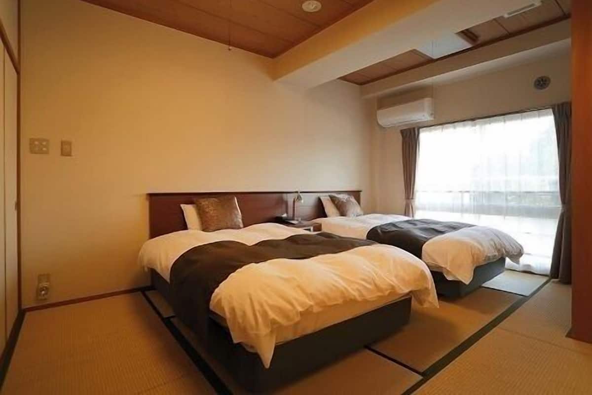 Ein Hotelzimmer mit zwei Betten, einer Holzbalkendecke und einem großen Fenster.