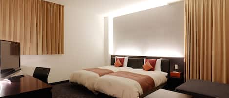 Una habitación de hotel con una cama, un escritorio, una silla, un televisor y cortinas.