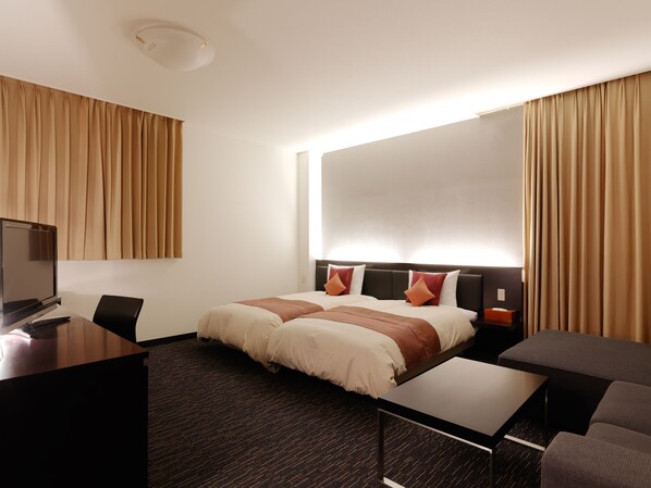 Una habitación de hotel con una cama, un escritorio, una silla, un televisor y cortinas.