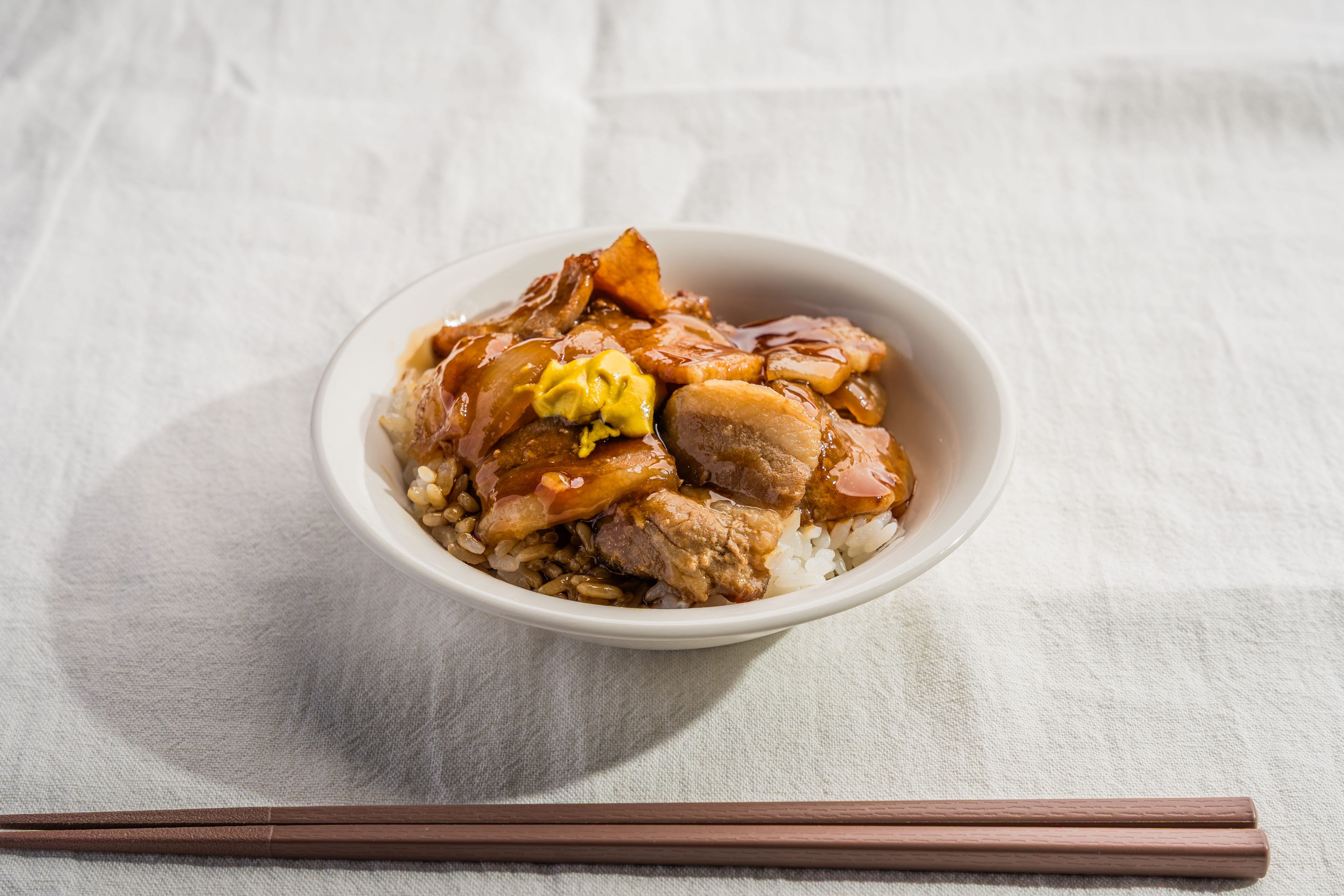 A bowl of food with rice, meat, and vegetables on a table.