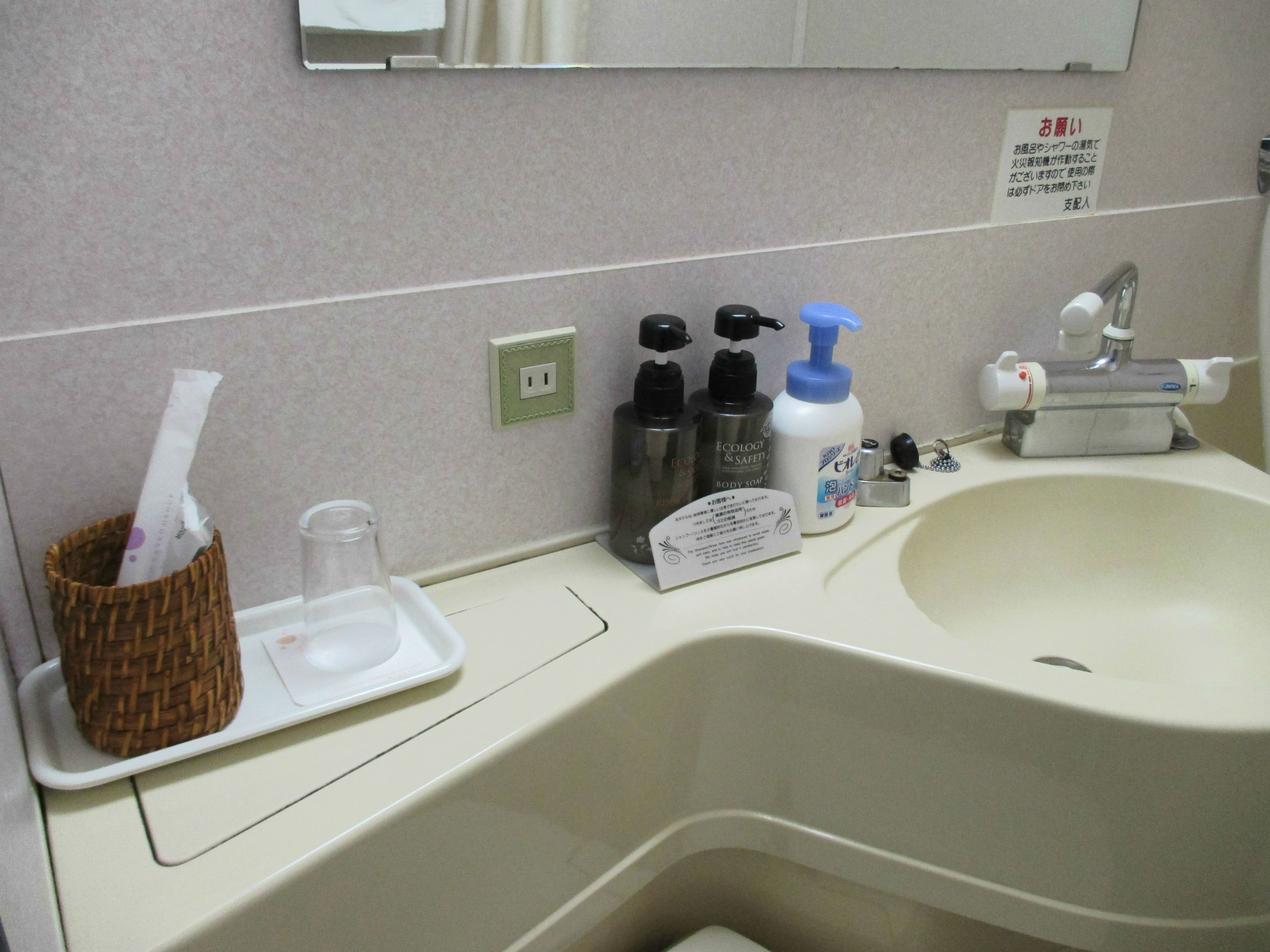 A bathroom sink with toiletries, a mirror, and a sign.