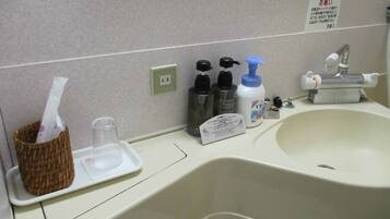 A bathroom sink with toiletries, a mirror, and a sign.