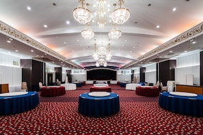 A spacious conference room with round tables, a stage, and ornate chandeliers. - Muroran Prince Hotel (Muroran)