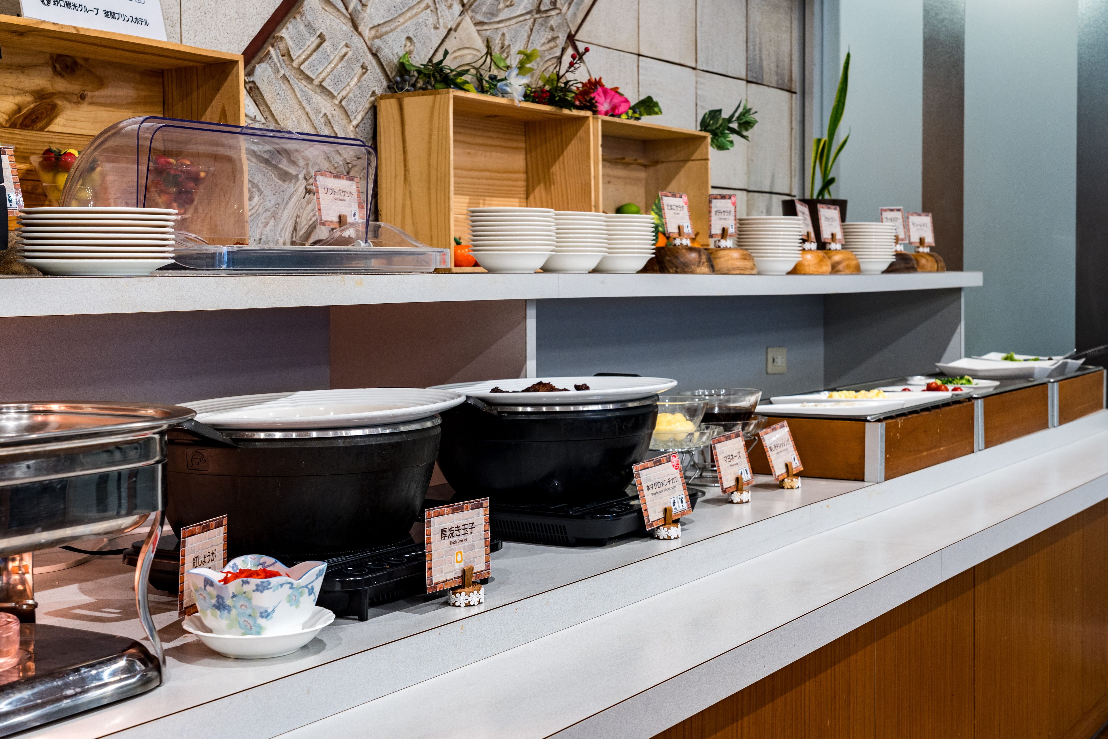 Una barra de buffet con distintos recipientes de comida y fuentes de servicio.