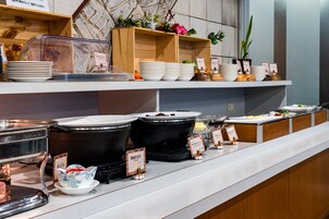 Una barra de buffet con distintos recipientes de comida y fuentes de servicio.
