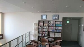 A lobby with a seating area, a bookshelf, and a door.