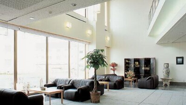 A spacious lobby with leather sofas, a wooden bench, and a large potted plant.