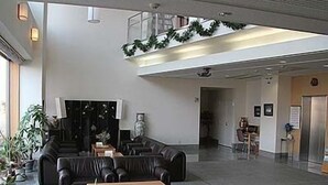 A spacious lobby with leather seating, a reception desk, and a staircase leading to an upper level.