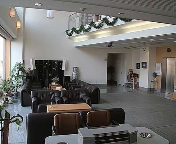 A spacious lobby with leather seating, a reception desk, and a staircase leading to an upper level.