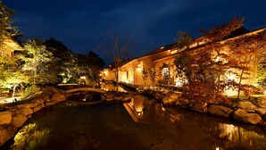 A traditional Japanese-style building with a koi pond and a stone bridge. - Beniya (Awara)