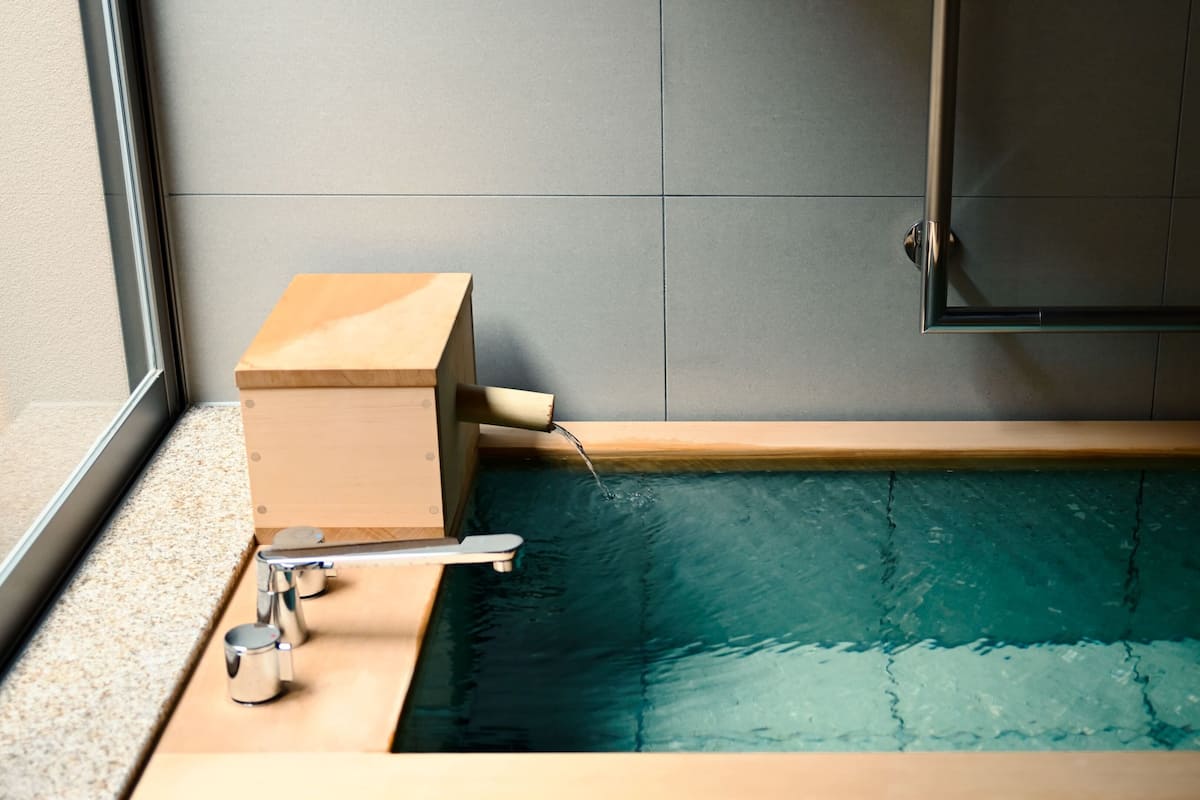 A bathtub with a wooden frame, a faucet, and a showerhead.