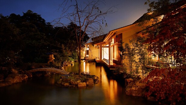 A traditional building with a water feature, stone bridge, and surrounding vegetation. - Beniya (Awara)