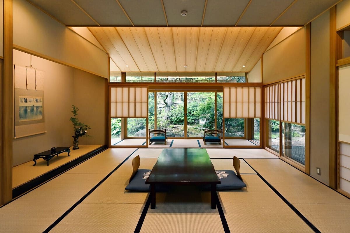 A traditional Japanese room with tatami flooring, a low table, and sliding doors.