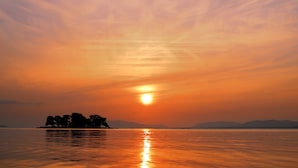 A sunset over a calm body of water with a silhouette of trees on an island. - Matsue Plaza Hotel Annex (Matsue)