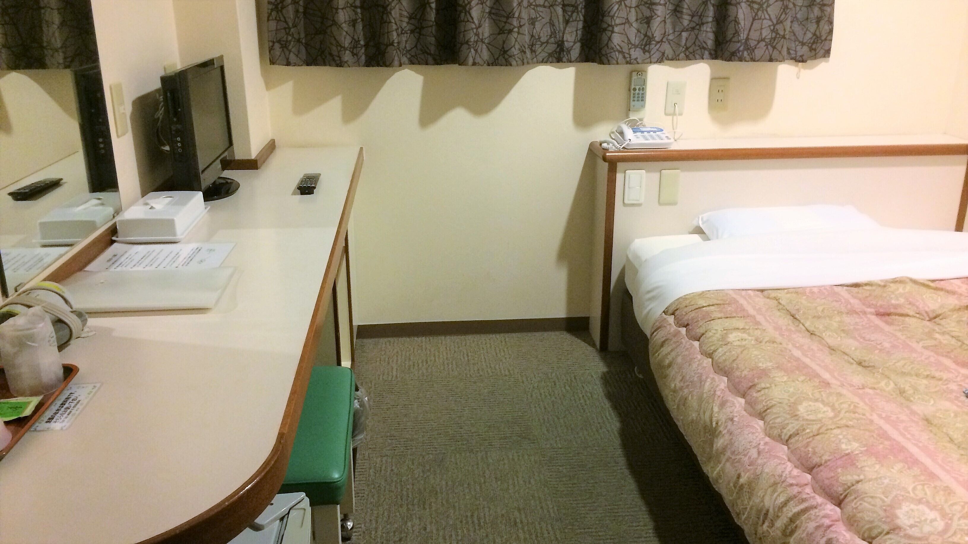 Una habitación de hotel con escritorio, silla, cama, mesita de noche y teléfono.