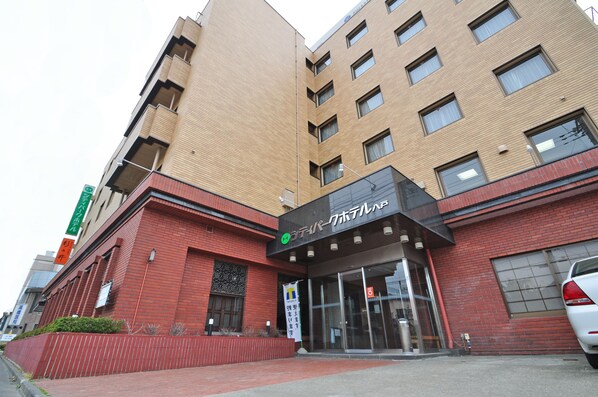 Un edificio de varios pisos con fachada de ladrillo rojo y una entrada negra.