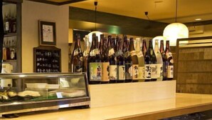 A bar area with a counter displaying bottles and a glass case with food items. - Takamatsu Hotel Sakika (Takamatsu)
