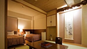 A room with two beds, a wooden table, a chair, a small cabinet, and a window with a view. - Takamatsu Hotel Sakika (Takamatsu)