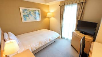 Quarto de hotel com cama, escrivaninha, televisão, candeeiro e um quadro na parede.