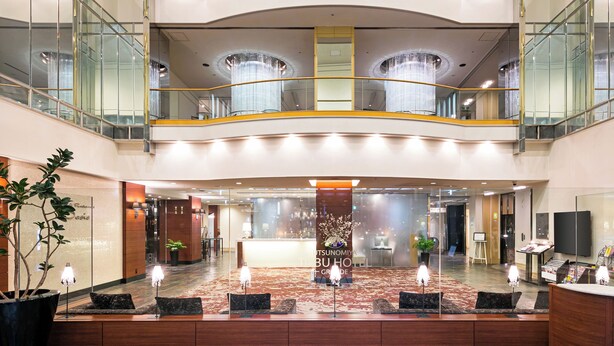 Un hall de hotel con una recepción, zona de estar y una araña.