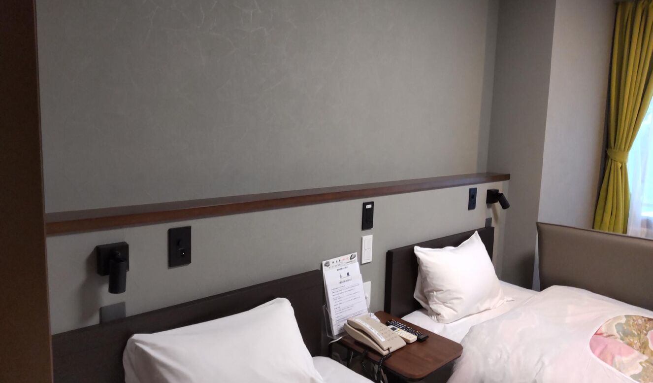 Una habitación de hotel con cama, mesita de noche y teléfono en la pared.