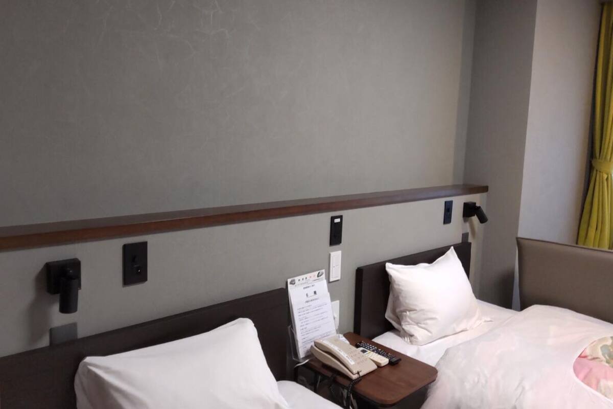 Une chambre d’hôtel équipée d’un lit, d’une table de chevet et d’un téléphone fixé au mur.