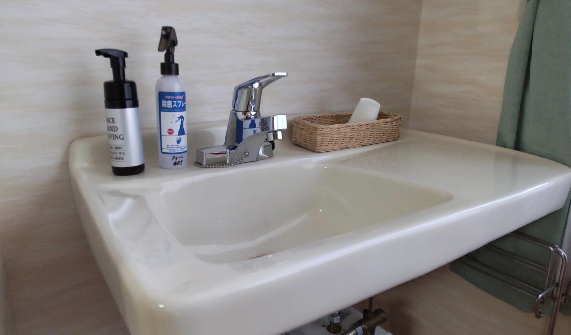 A bathroom sink with a bottle of hand soap, a bottle of lotion, and a small basket with a tissue.
