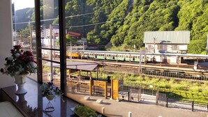 A train station with multiple tracks, a platform, and a building with a sign.
