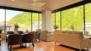 A spacious room with large windows, a sofa, patterned chairs, and a dining area.