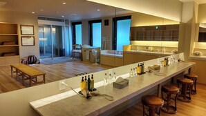 A modern kitchen with a long countertop, bar stools, and a dining area with a table and chairs.