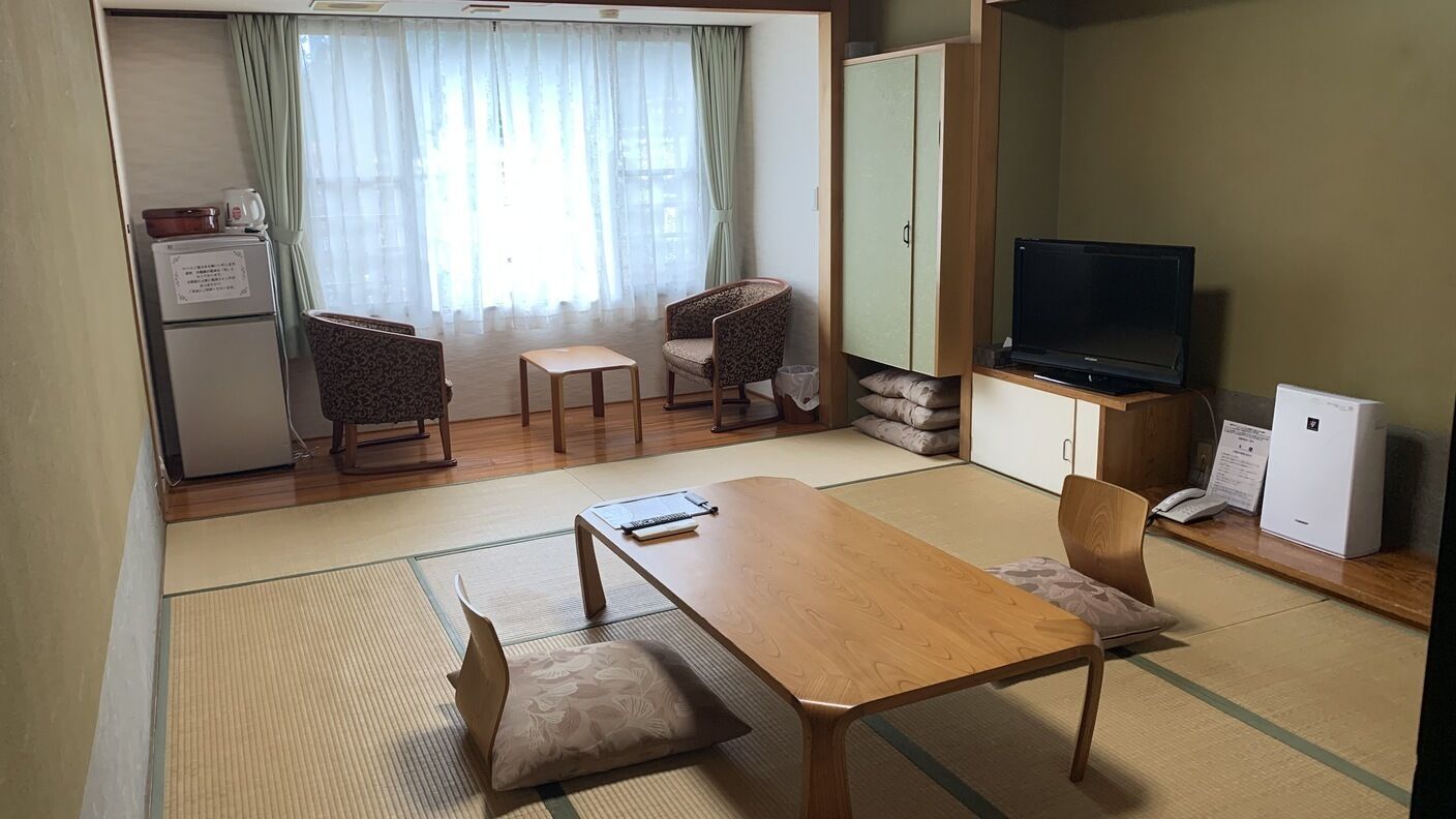 Un espacio habitable compacto con una mesa de madera, dos sillas, un televisor, un armario y un refrigerador.