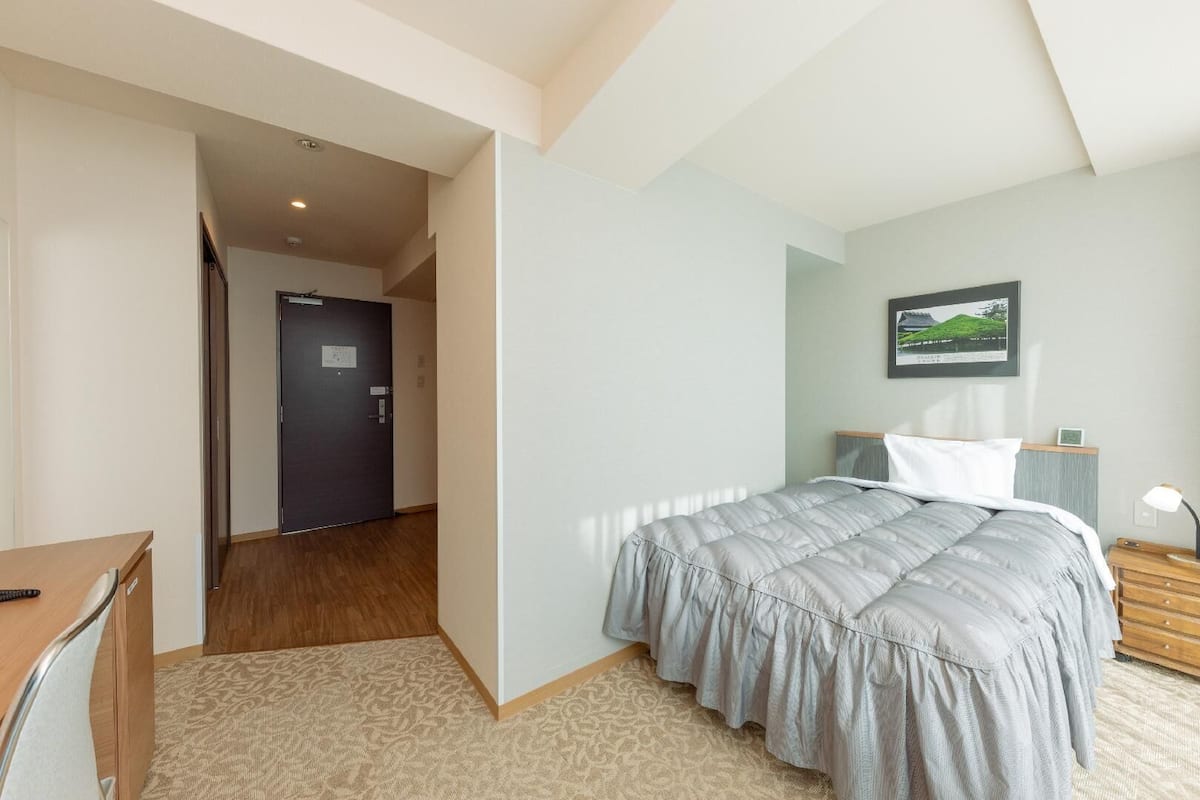 Een slaapkamer met een bed, een bureau en een stoel.