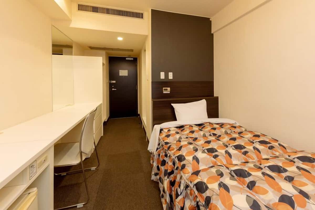 Una habitació d'hotel amb un llit, una taula de treball i una cadira.