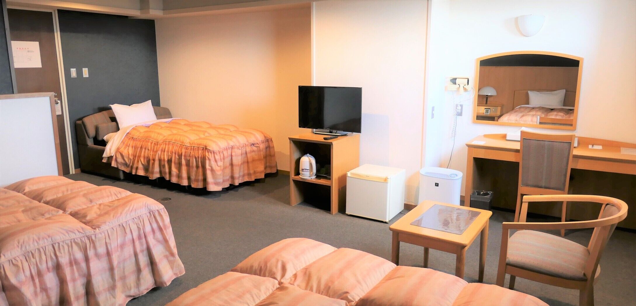 A hotel room with a bed, a desk, a chair, a television, and a small table.