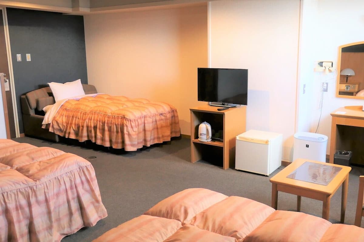 Habitació d'hotel amb llit, escriptori, cadira, televisió i taula petita.