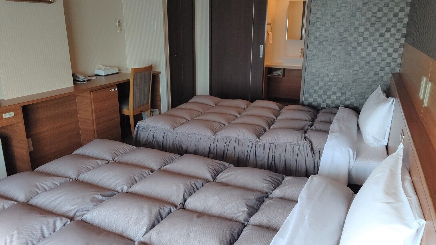 A compact room with a bed, a desk, and a small bathroom area.