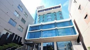 A multi-story building with a modern architectural design, featuring a prominent glass facade and a staircase leading to the entrance. - Marugame Plaza Hotel (Marugame)