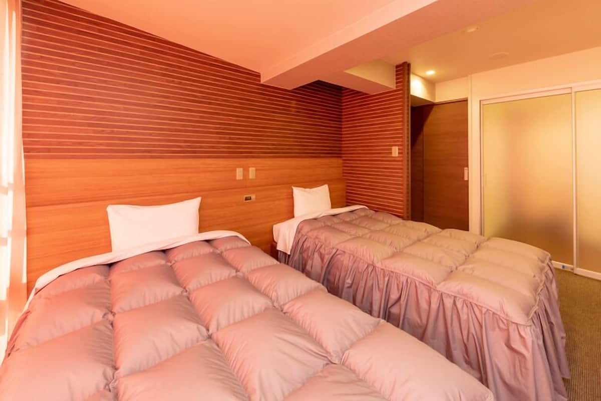 Habitació d'hotel amb dos llits, panells de fusta a les parets i un armari amb portes corredisses.