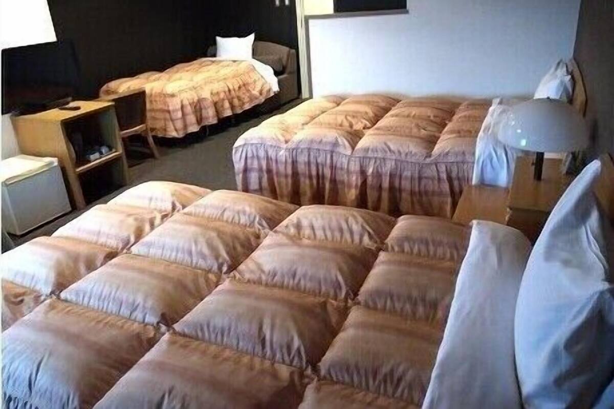 Een hotelkamer met meerdere bedden, een bureau, een stoel en een lamp.