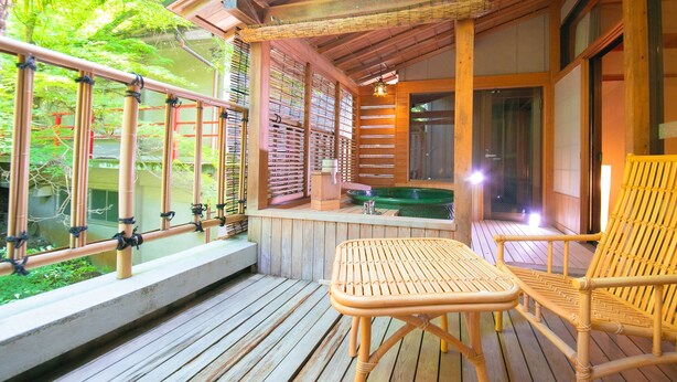 Een houten terras met een tafel en stoelen, een kleine hottub, en uitzicht op groen.