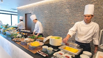 Un buffet proposant une variété de plats, avec des chefs qui servent les clients.