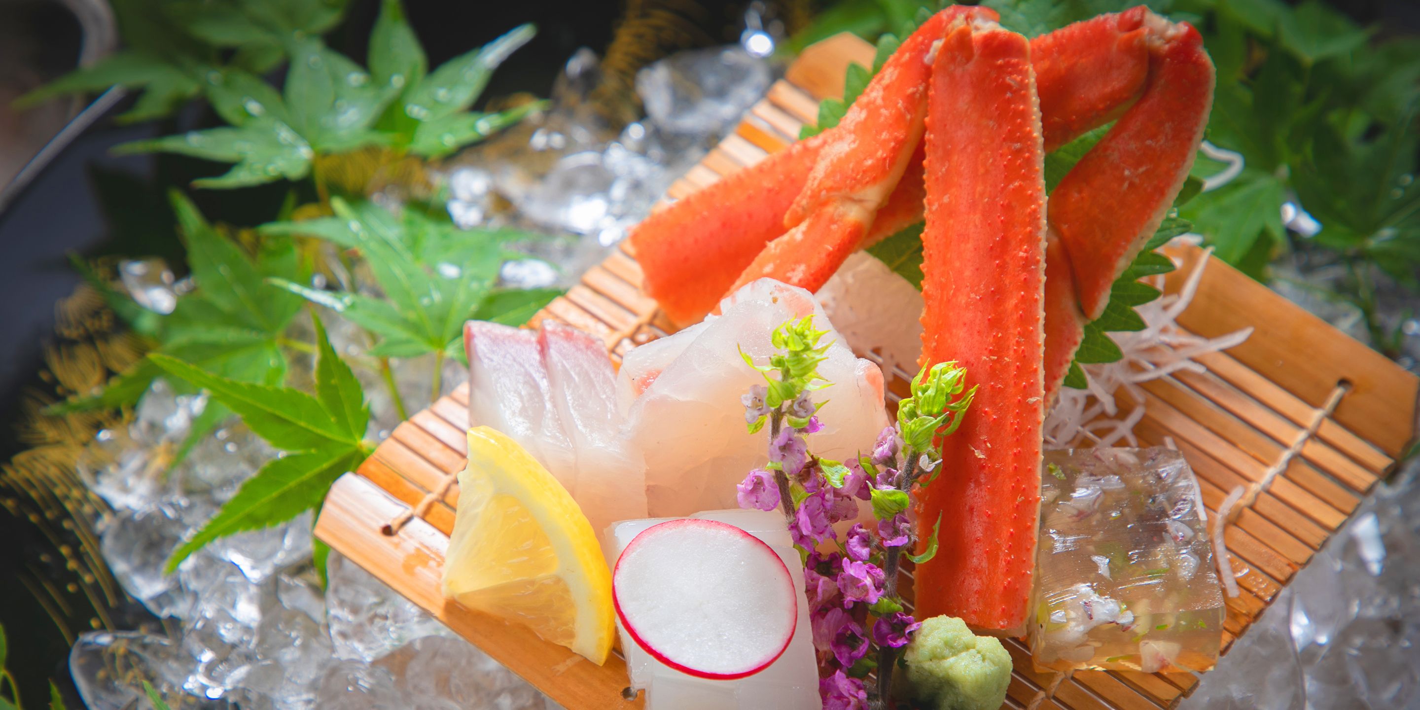 A tray with various food items including fish, lemon, radish, and flowers on ice.