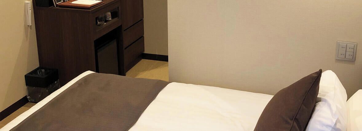 Ein Hotelzimmer mit einem Bett, einem Holzschrank und einem Mülleimer.