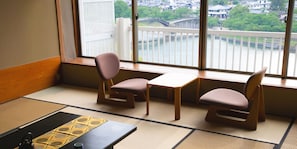 Een kamer met tatami vloeren, twee houten tafels en twee stoelen.