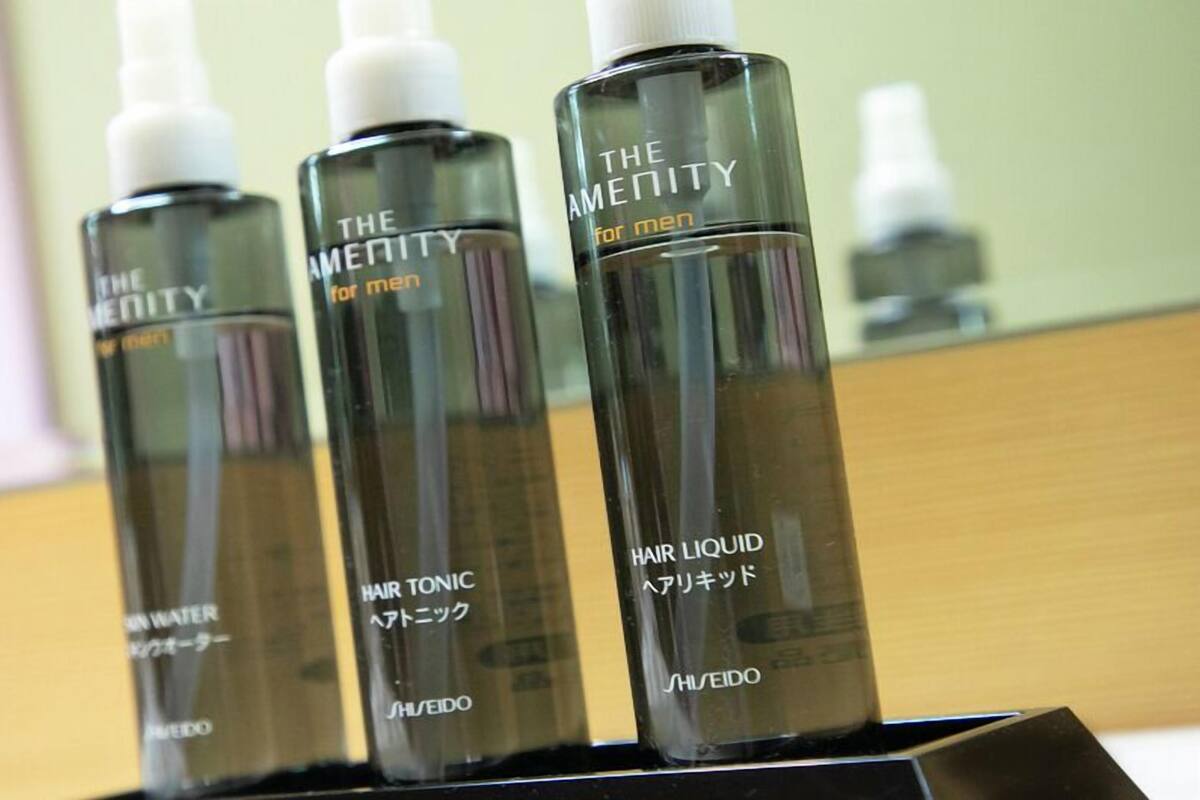 Trois flacons de lotion capillaire sur un présentoir noir.