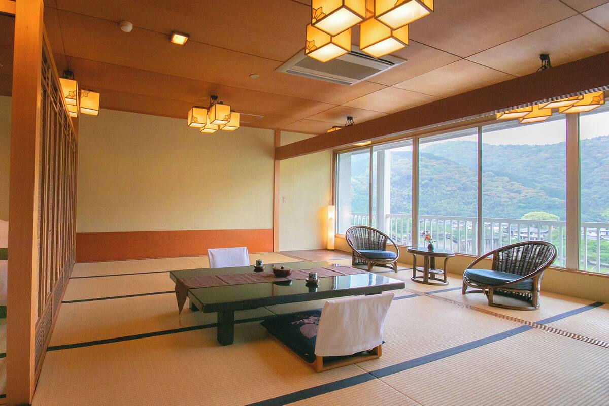 Une pièce de style japonais traditionnel, avec un sol recouvert de tatamis, une petite table basse, deux chaises et un lit.