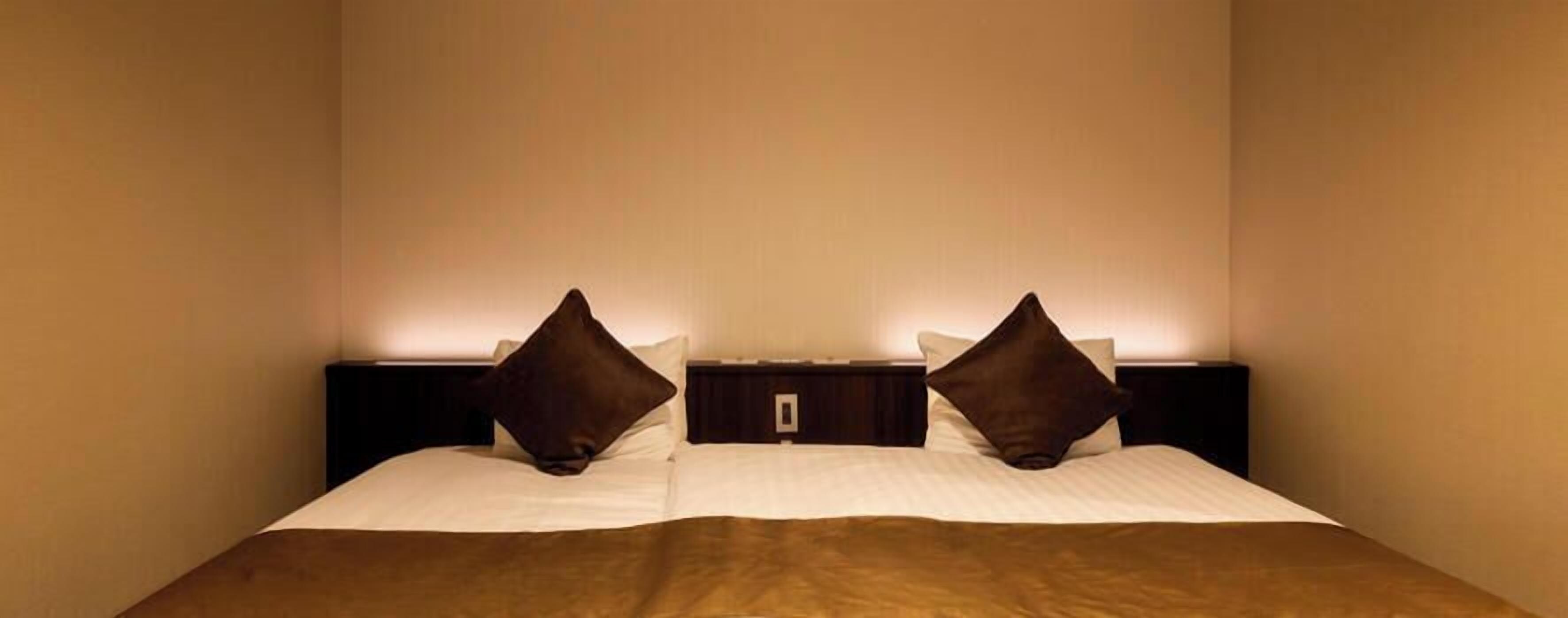 Ein Hotelzimmer mit einem Bett, zwei Nachttischen und einer Wandleuchte.