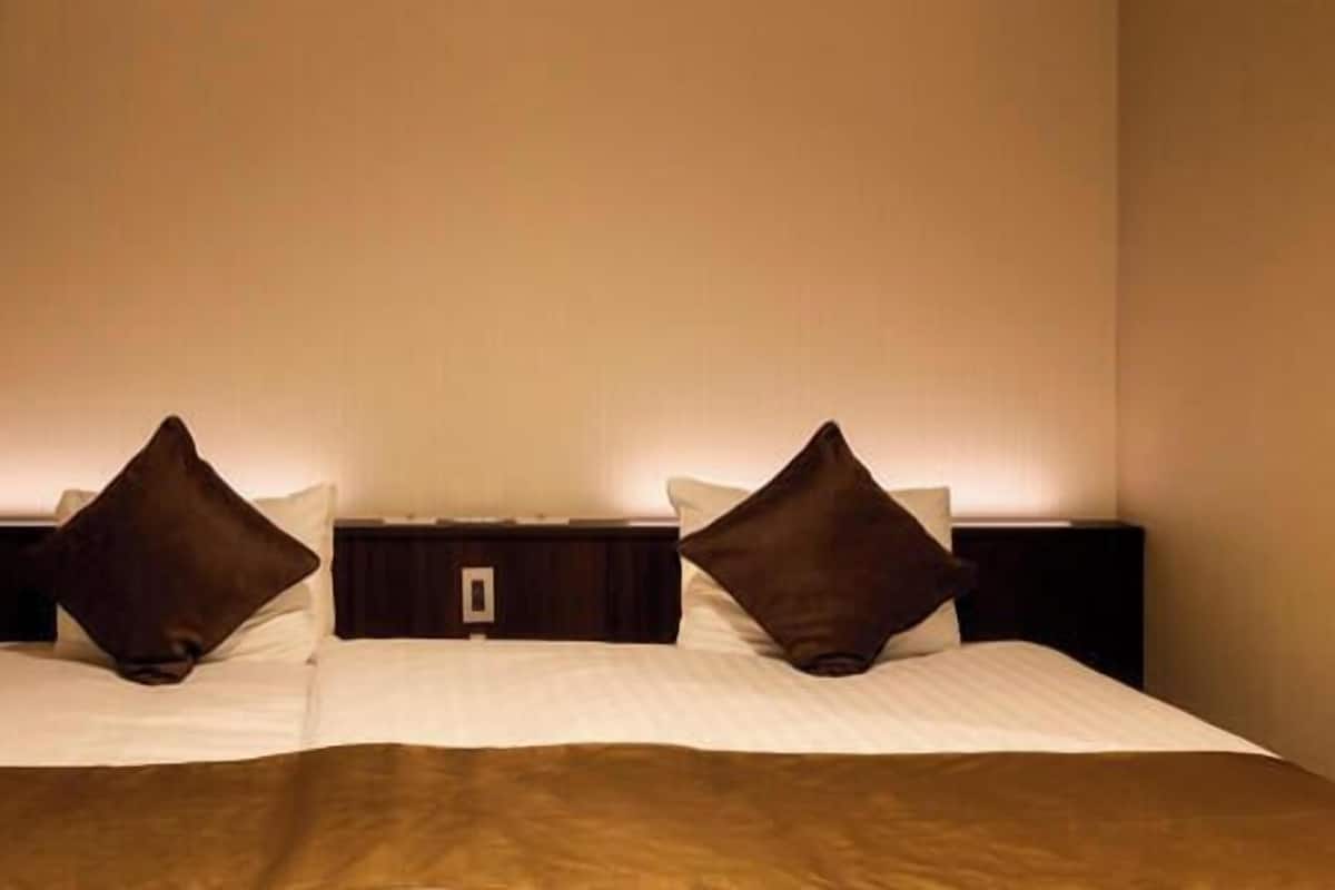 Une chambre d’hôtel avec un lit, deux tables de chevet et un luminaire fixé au mur.